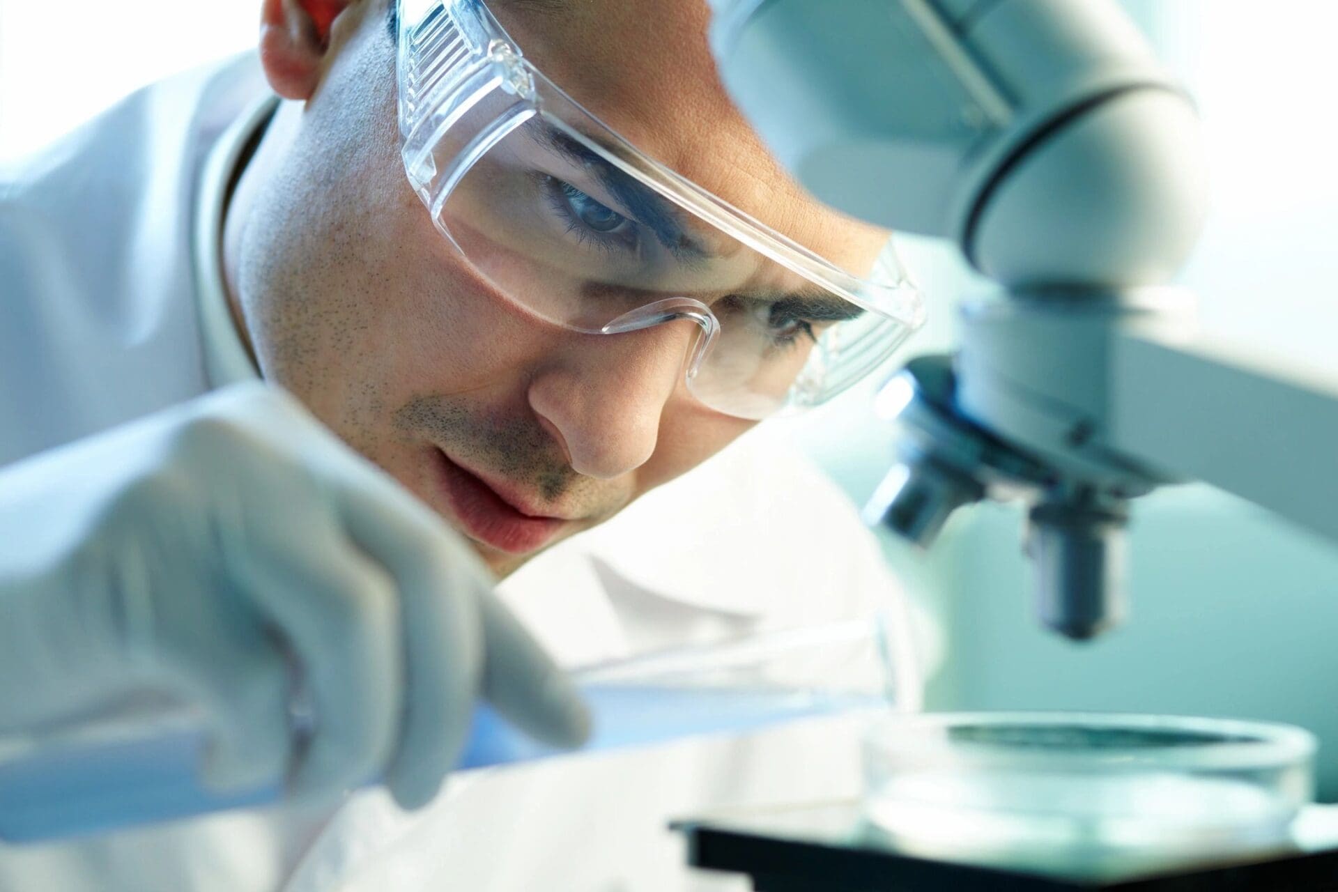 A man in lab goggles looking at something on the table.